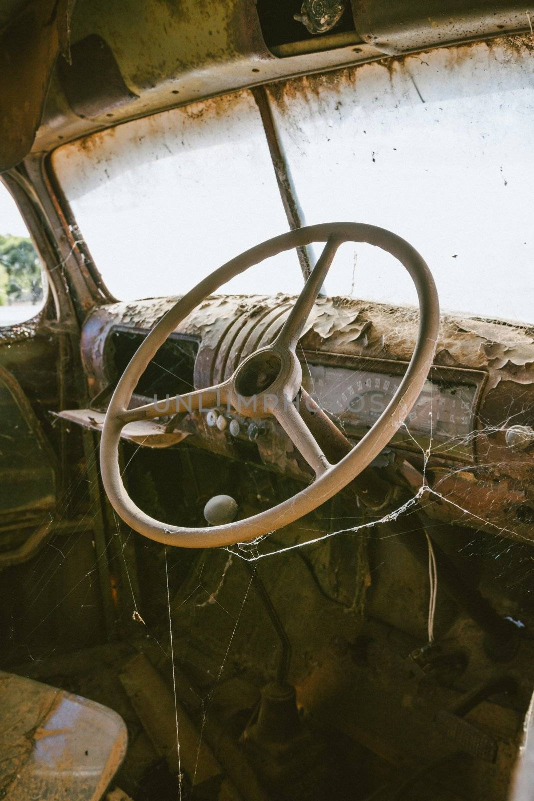 Old rusted truck steering wheel with spider web by hangingpixels
