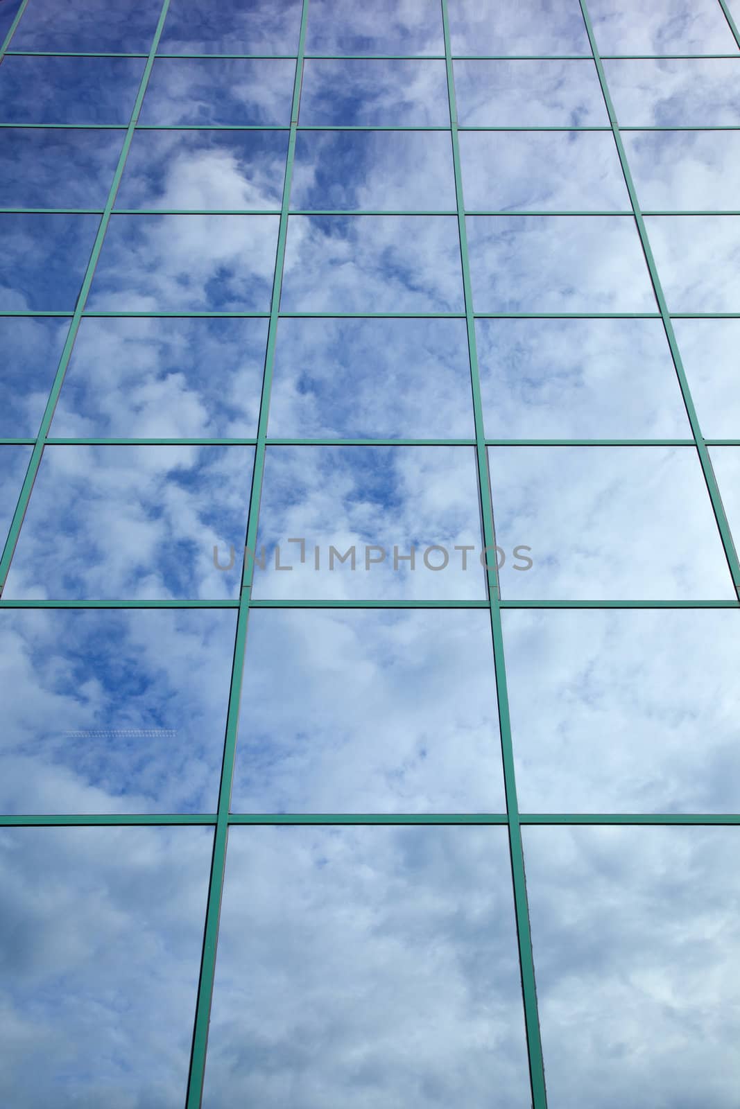 clouds and blue sky reflected in glass facade by ahavelaar