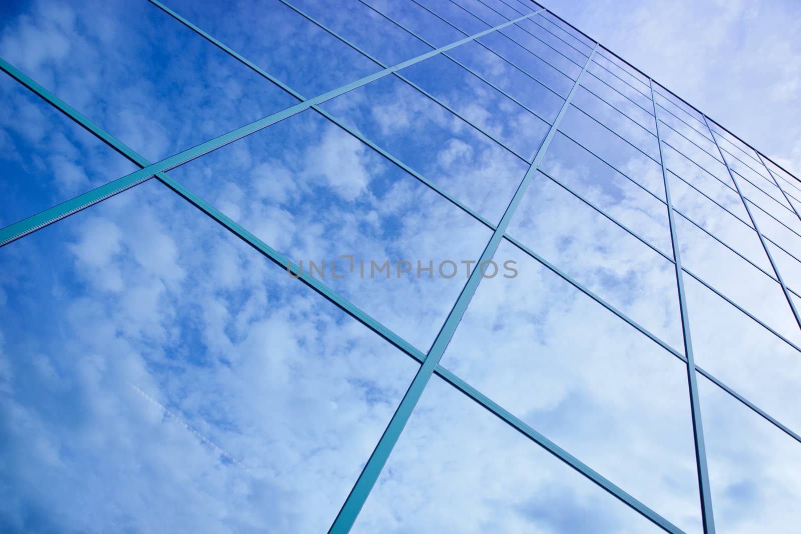 reflections of clouds and blue sky in facade of office building