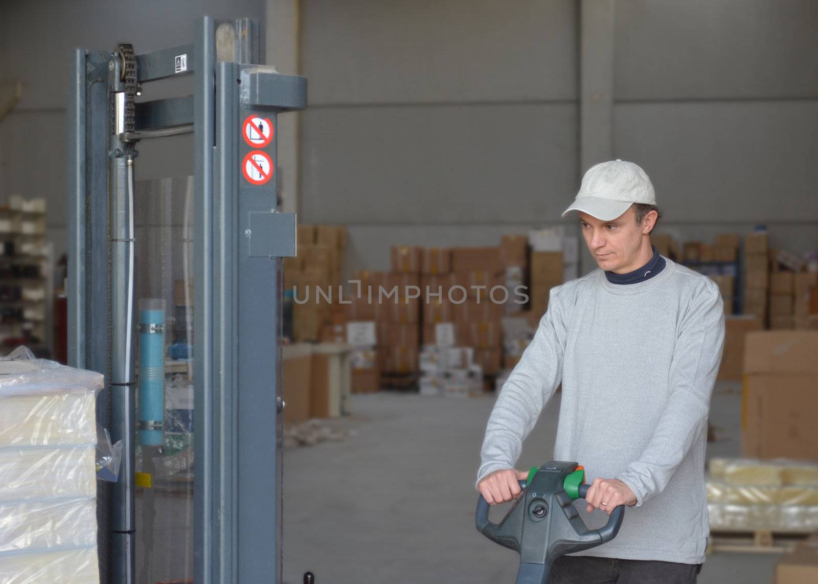 Good looking guy at forklift picking and moving packages in a warehouse