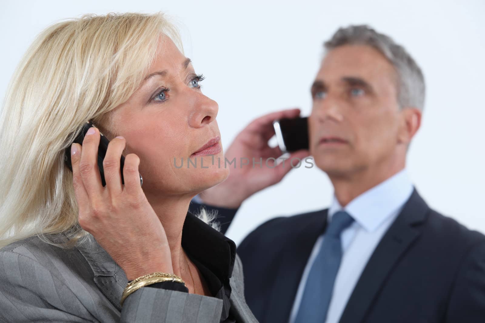 businessman and businesswoman talking on their cells