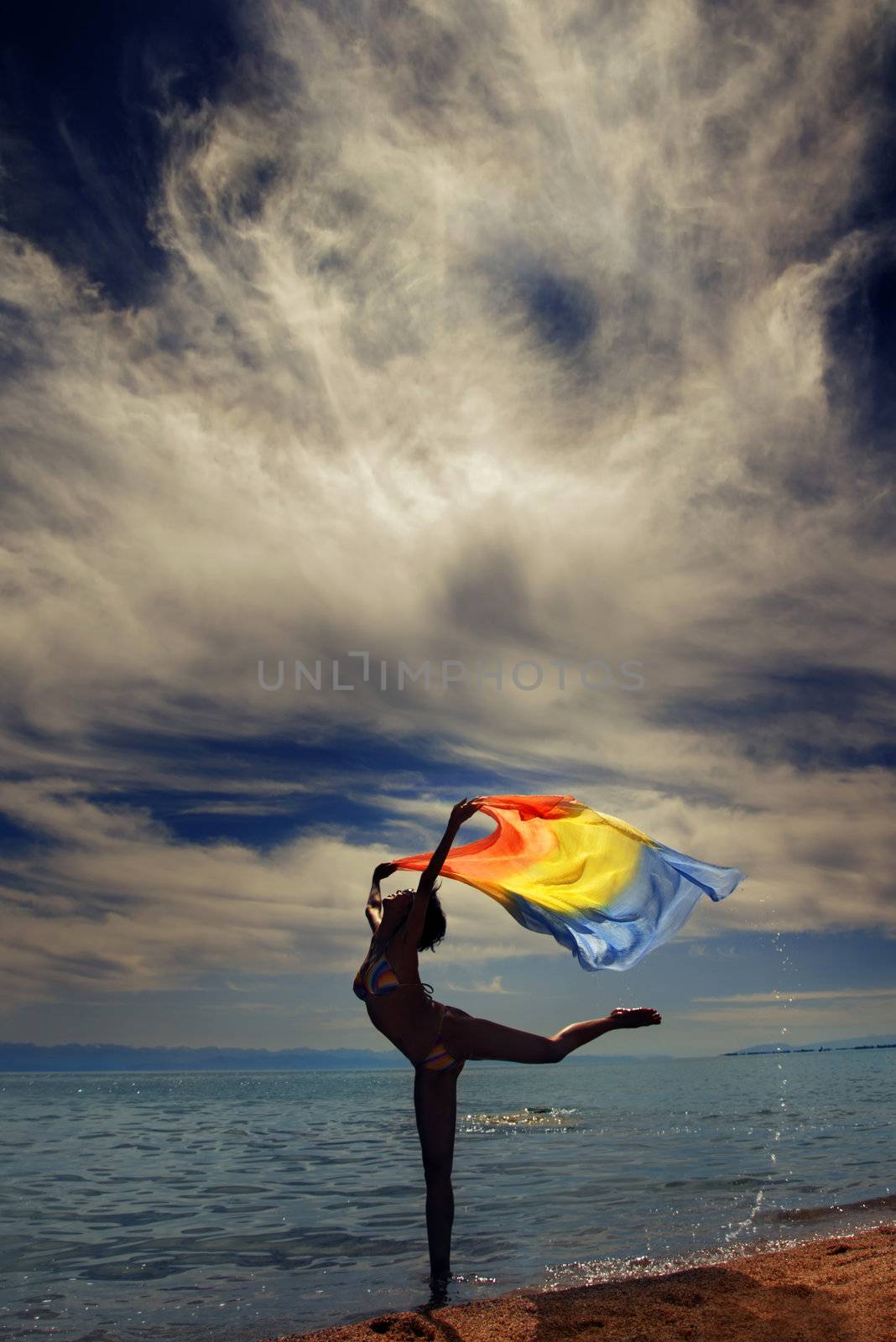 Photo of the dancing lady at the sea during vibrant sunset