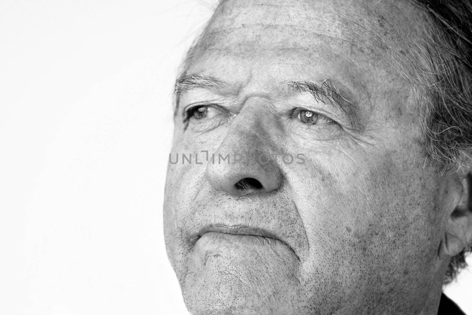 Black and white portrait of a senior man with pale eyes looking away with hint of a smile, great facial details, over white.