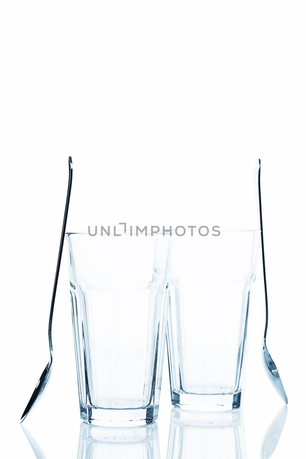 two empty latte macchiato glasses with standing spoons on white background