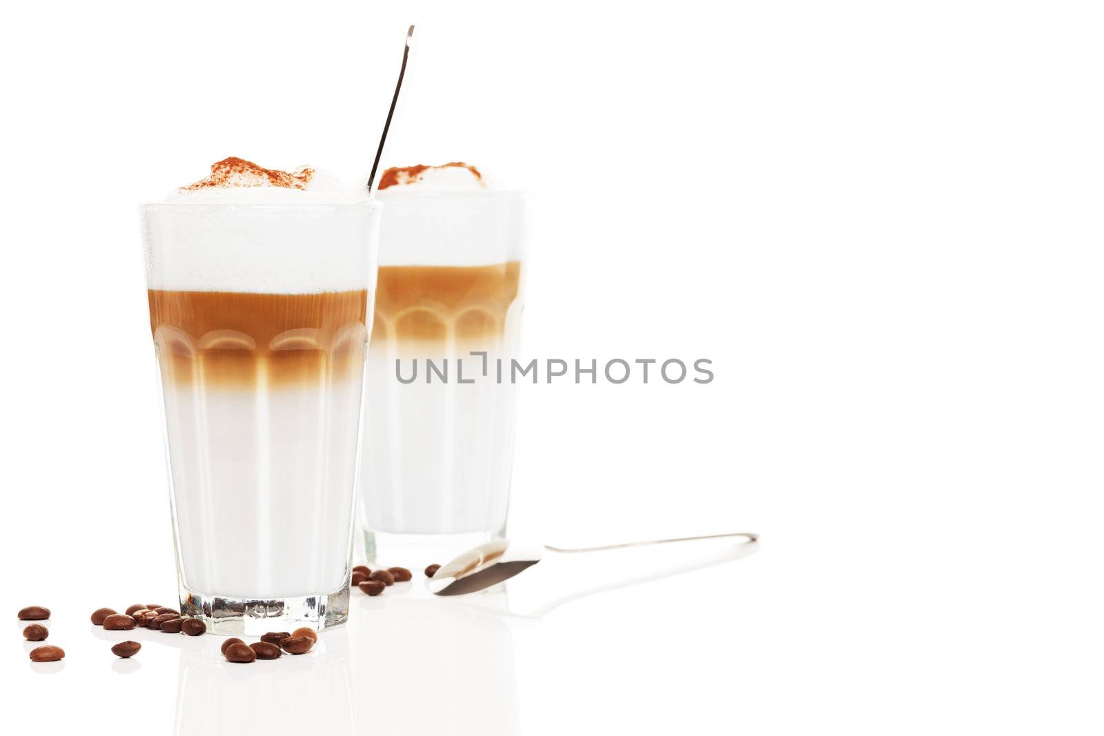 two glasses latte macchiato with coffee beans and chocolate powder on white background