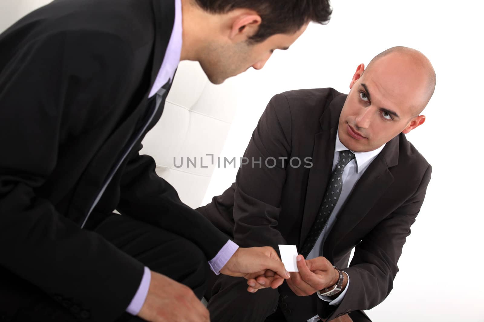 Businessmen exchanging cards by phovoir