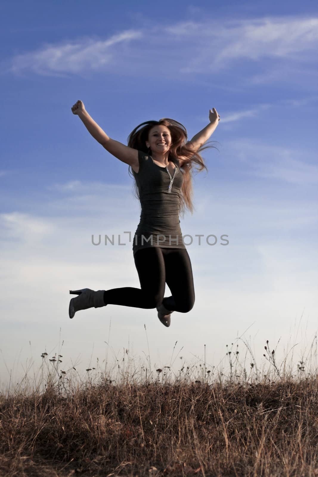 beautiful girl jumps against the blue sky