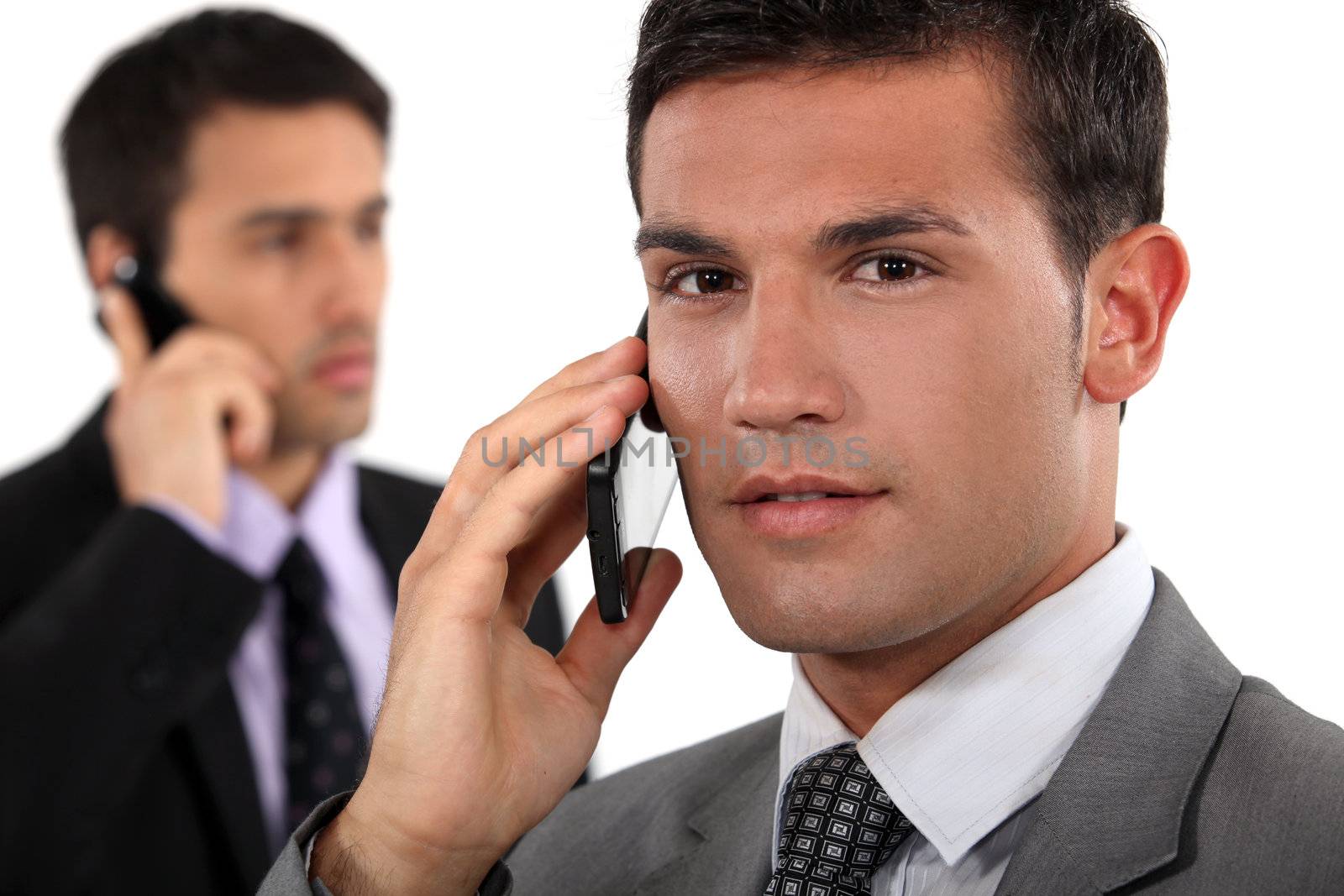 Businessmen talking on their mobile phones by phovoir