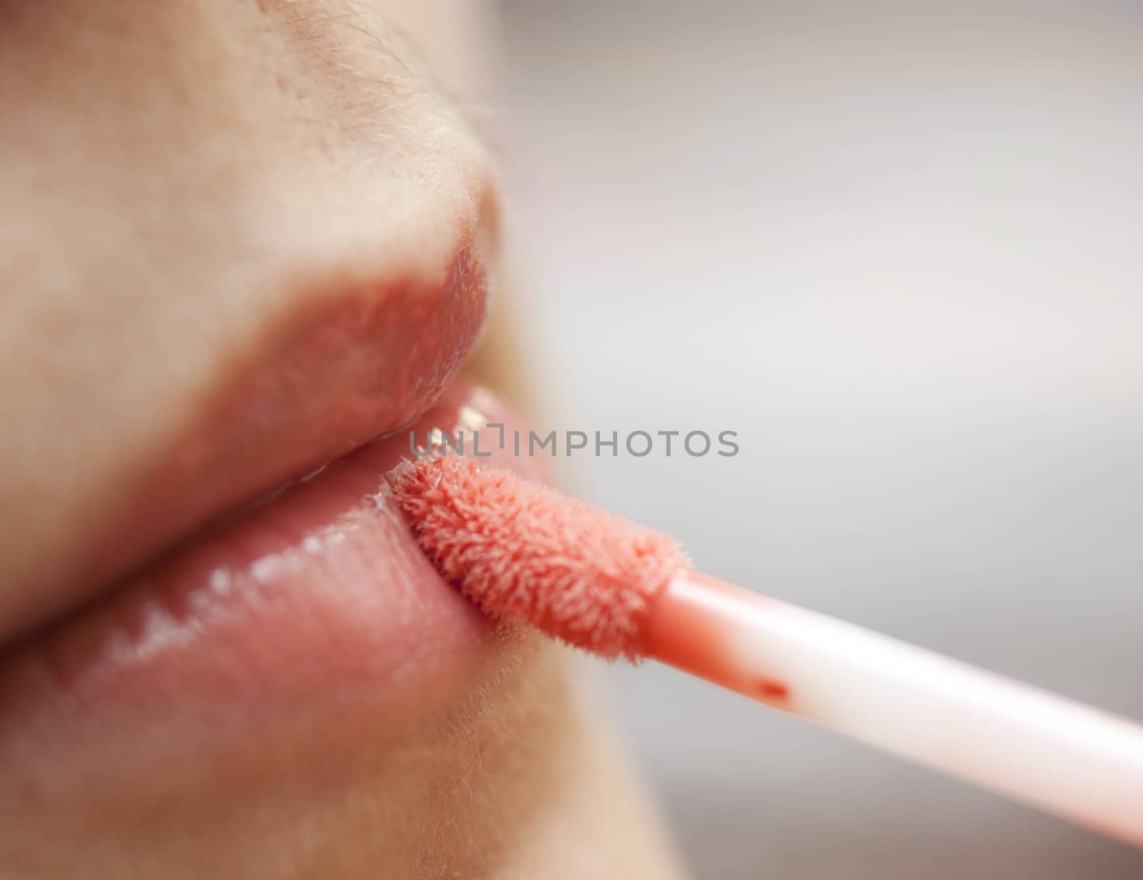 Close-up of a woman lips applying red lipstick.