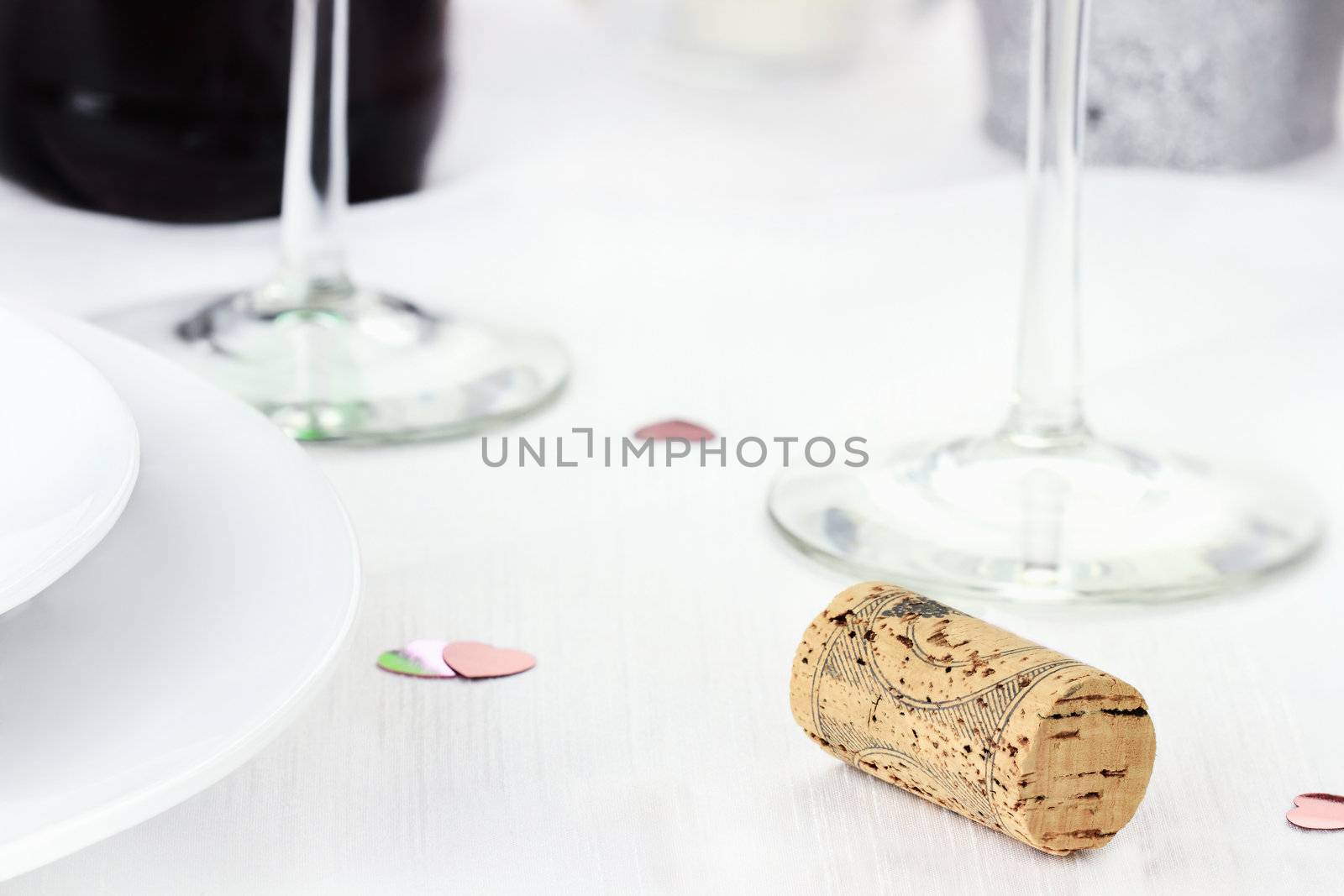Wine cork near dinner plates and wine glasses. Shallow depth of field.