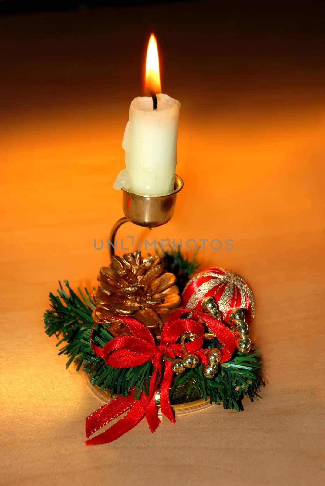 christmas burning candle over orange in decorative candlestick