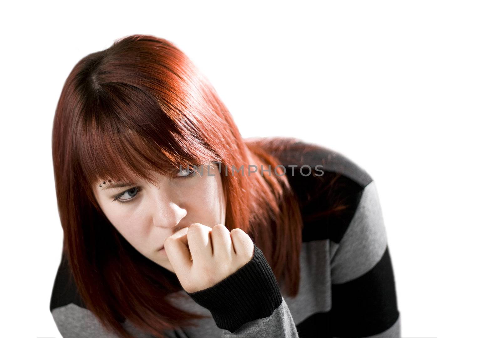 Pensive redhead girl biting her nails and checking out (looking away).

Studio shot.