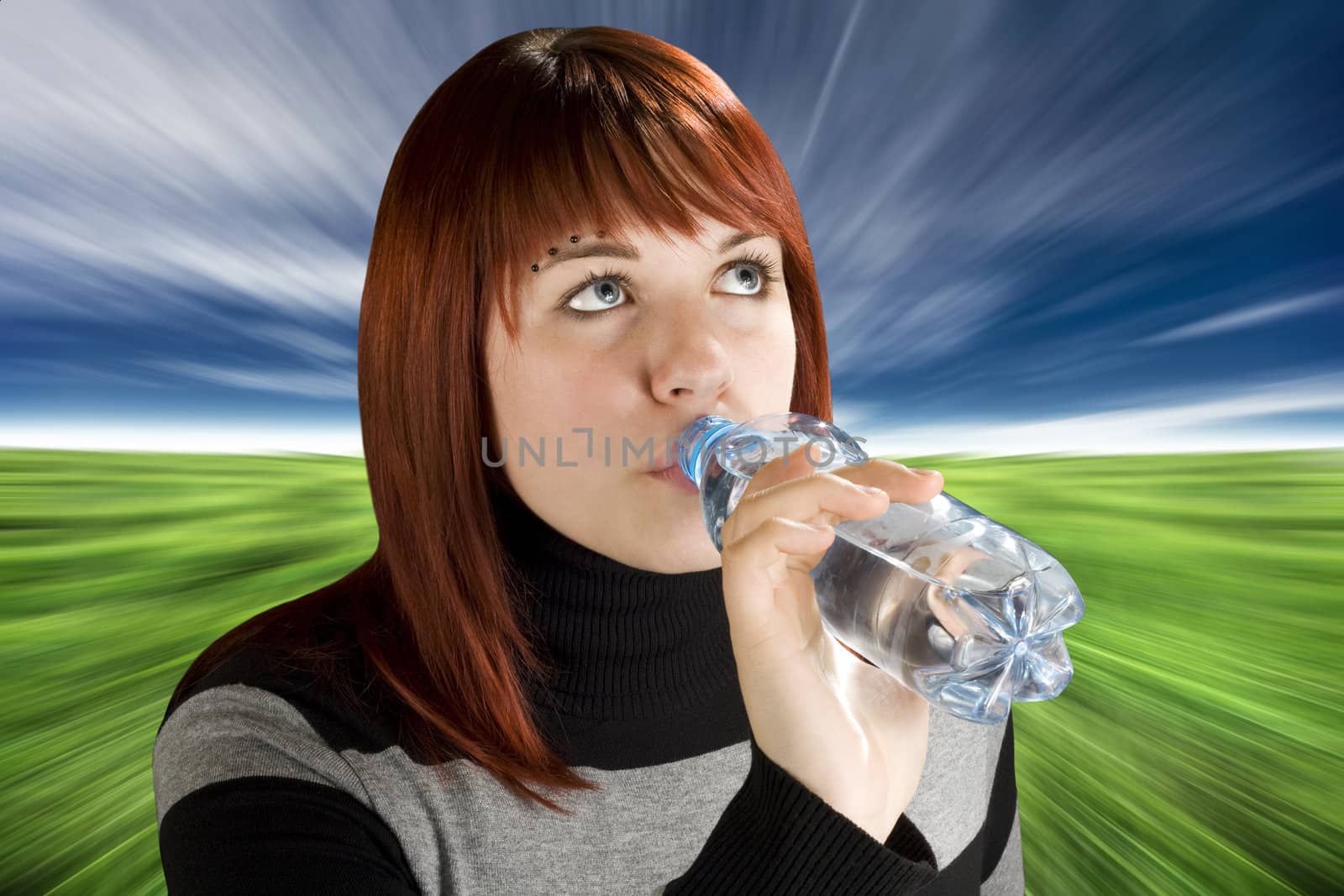 Beautiful girl with red hair drinking water, thirsty.

Studio shot.