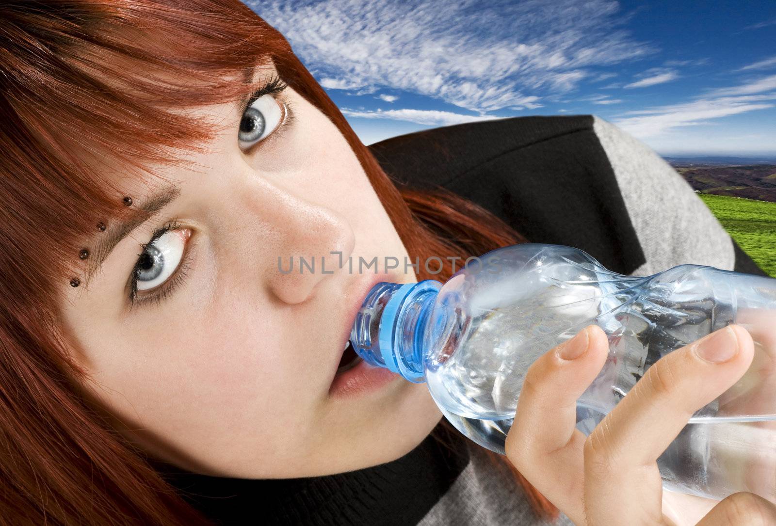 Seductive redhead girl looking at camera and drinking a bottle of water.

Studio shot.