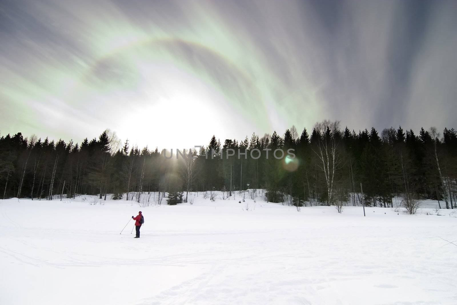 Skiing on a contrasty dramatic day.  A winter landscape looking into the sun with lens flare.