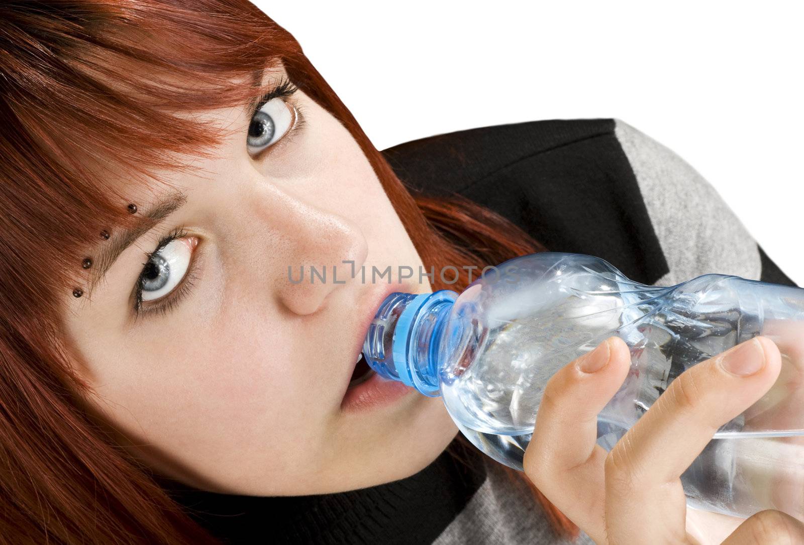Seductive redhead girl looking at camera and drinking a bottle of water.

Studio shot.