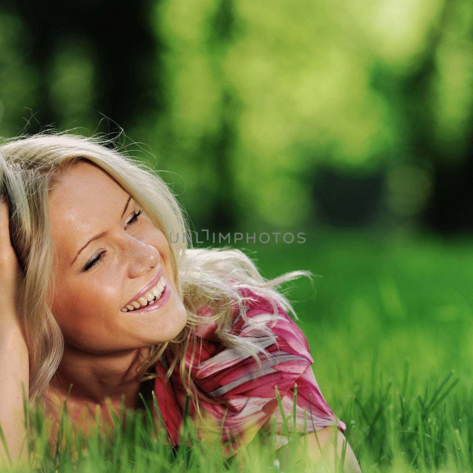 smile blonde lying on green grass