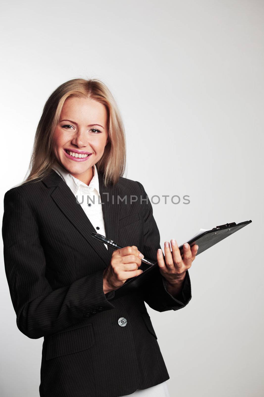 business woman writing in notebook on a gray background