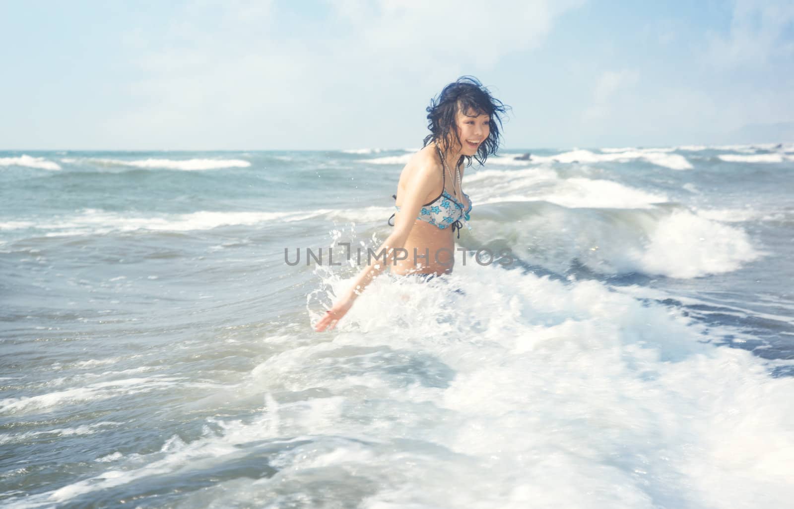 Happy brunette lady laughs and plays with water at summer beach