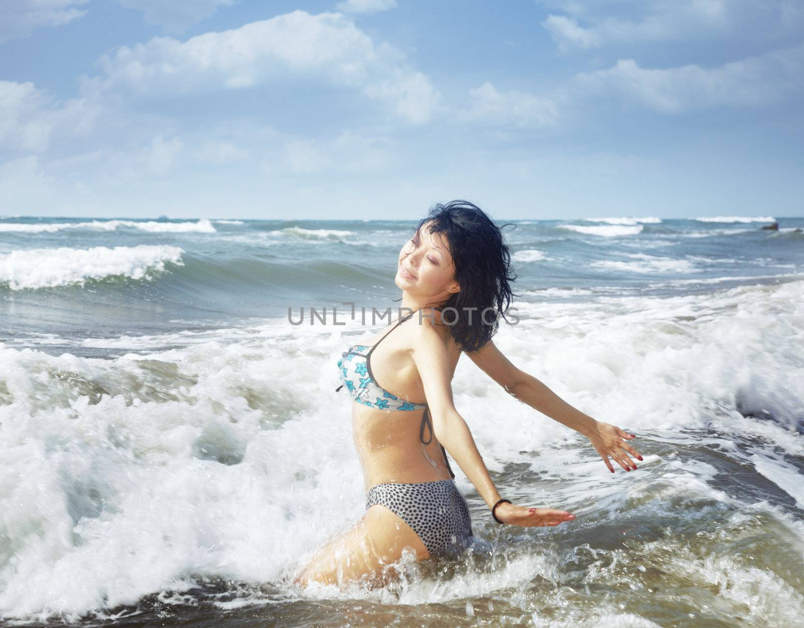 Smilig lady playing with waves at the sea resort during summer