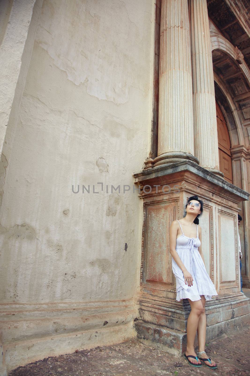 Brunette female tourist looking to the high column of the ancient historical temple. Natural light and colors