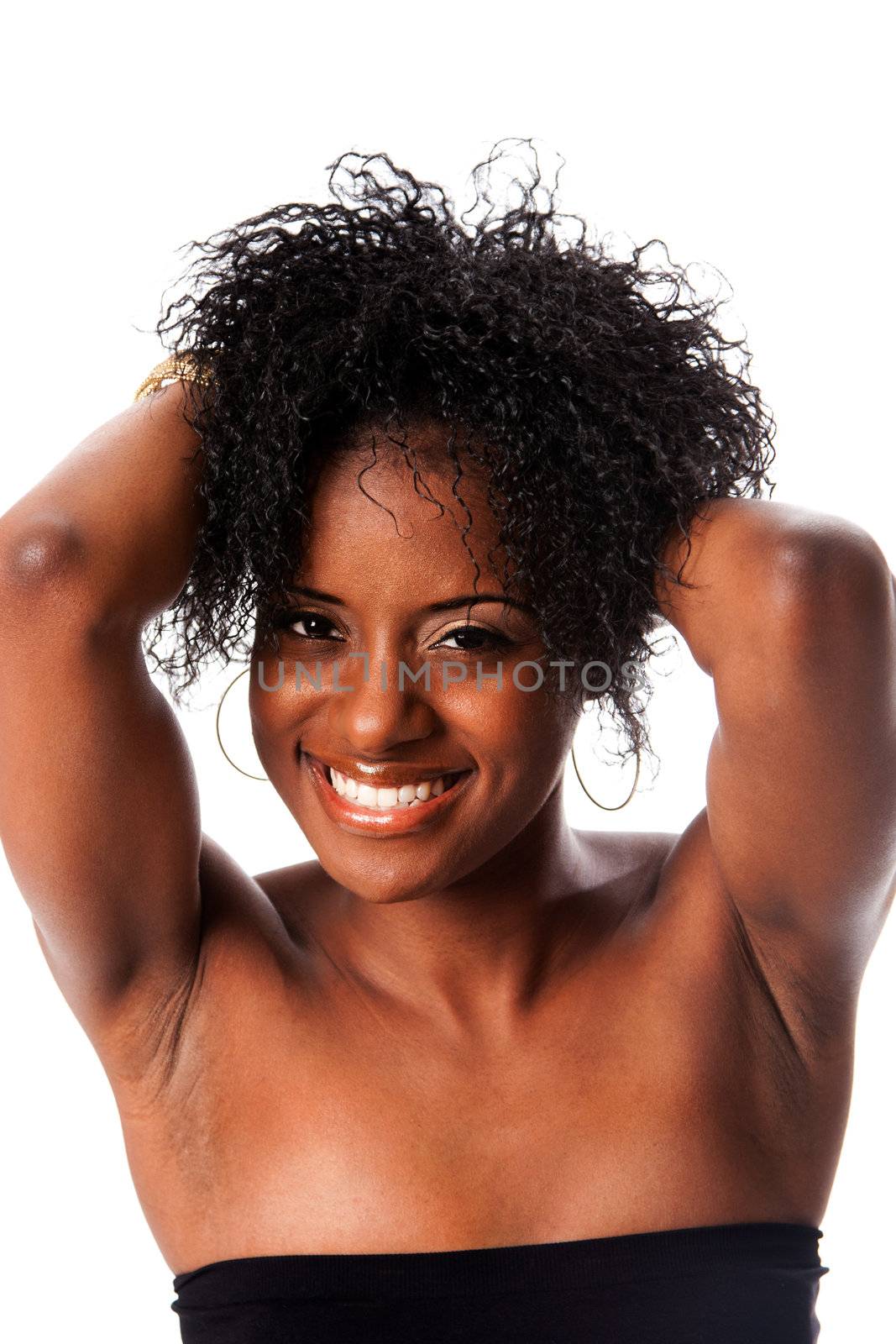 Face of a beautiful happy African woman smiling showing her white teeth and holding hands in curly hair, isolated.