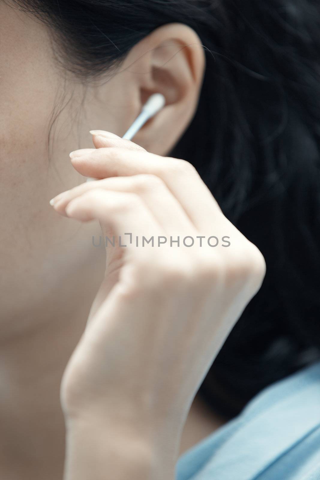 Woman holding cotton swab and cleaning ear