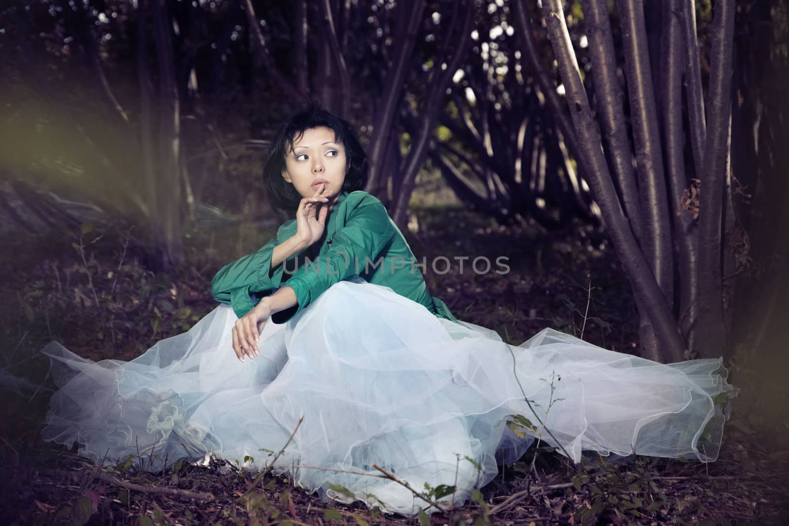 Fashionable lady in the autumn forest with blurred leaves on a foreground