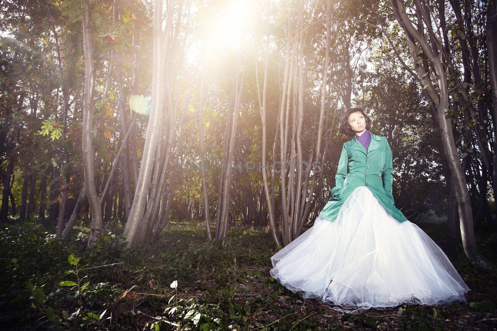 Lady in the wedding dress standing in the autumn forest with fog and red leaves. Natural light and flares