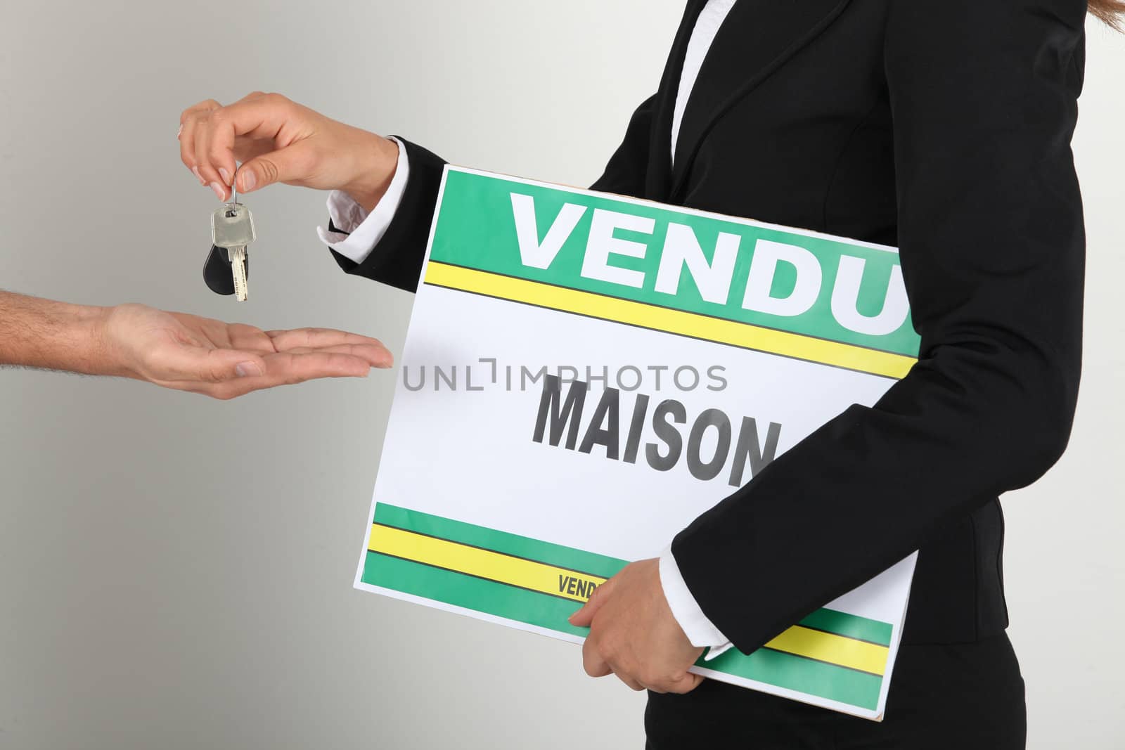 Estate-agent holding sold sign and handing keys to client
