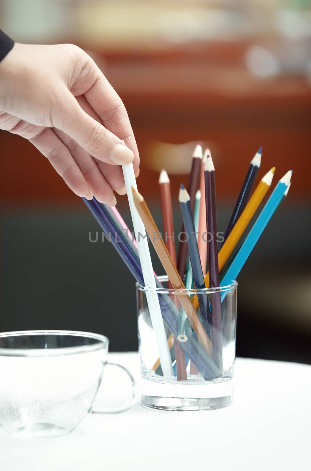 Human hand selecting colored pencil. Vertical photo