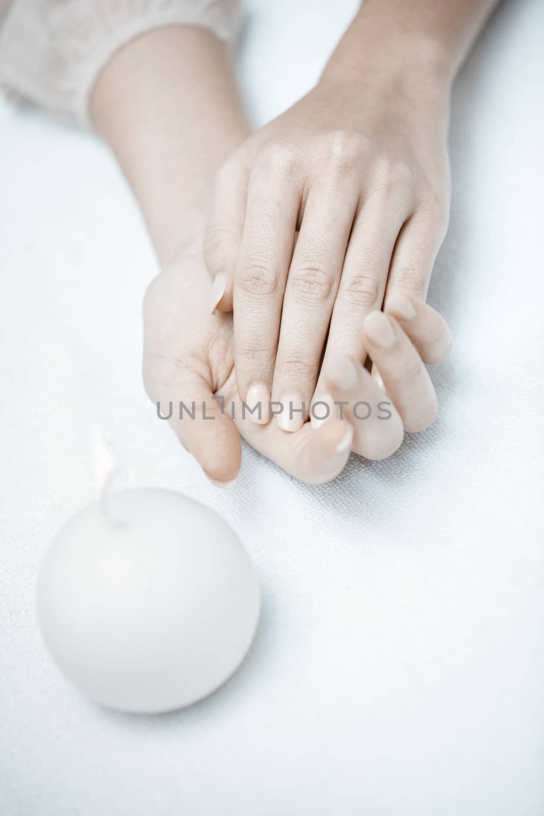 Woman hands in spa saloon with white candle
