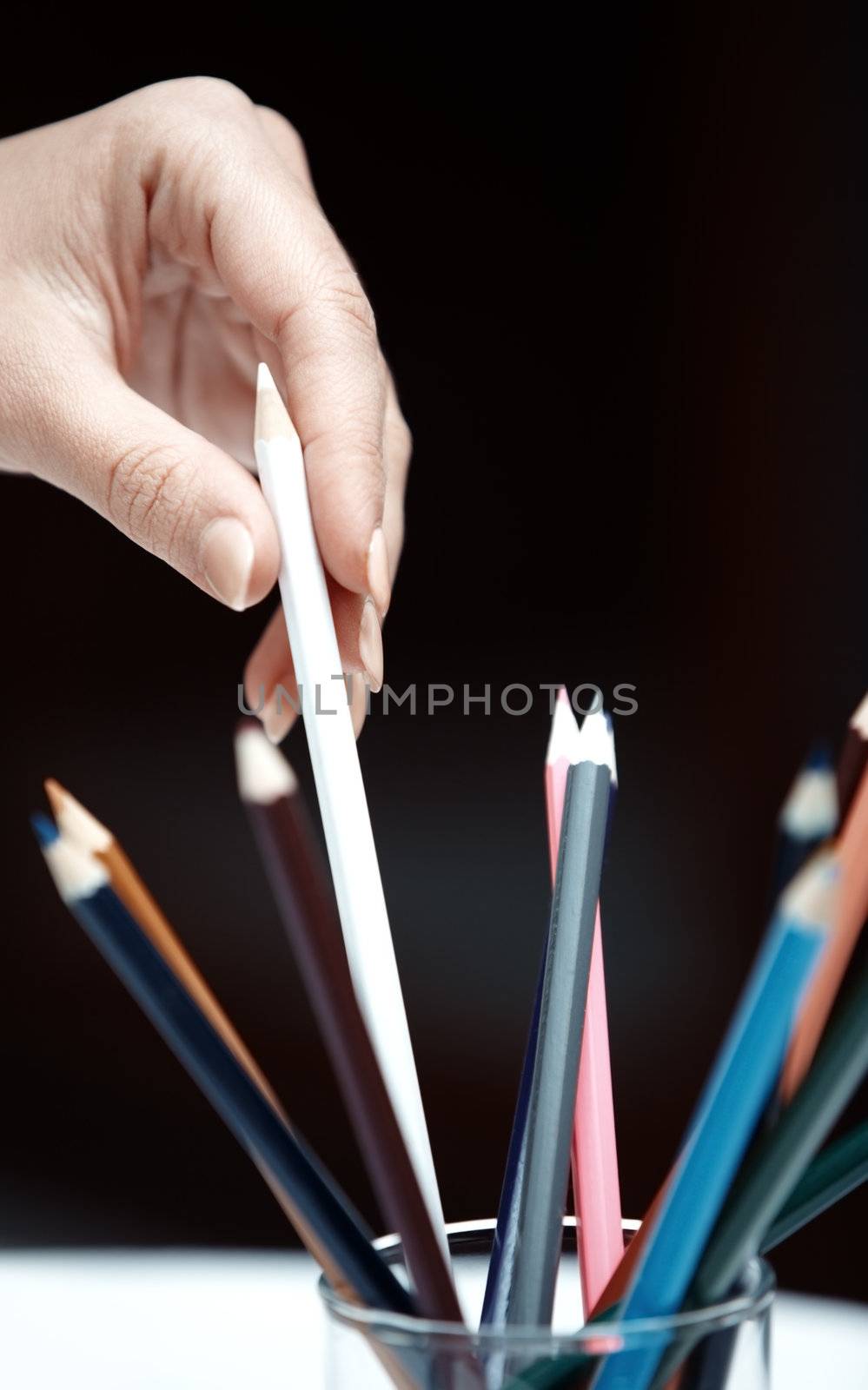 Human hand selecting colored pencil. Vertical photo