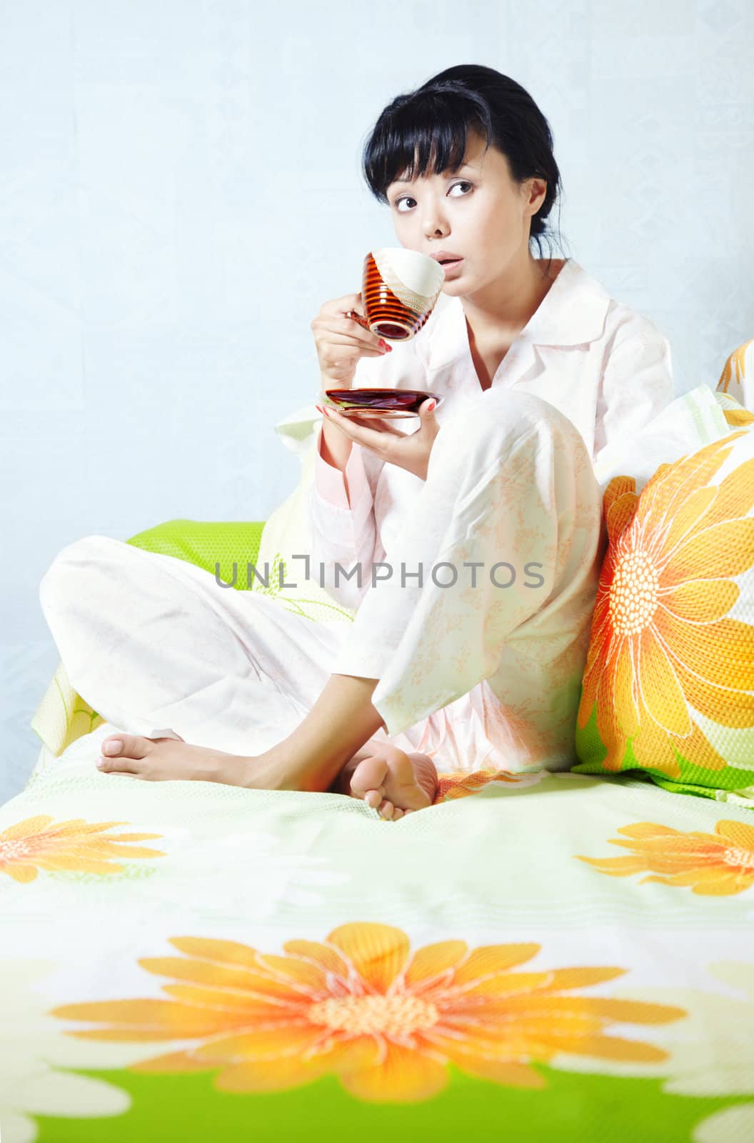 Lady sitting on the bed and drinking coffee