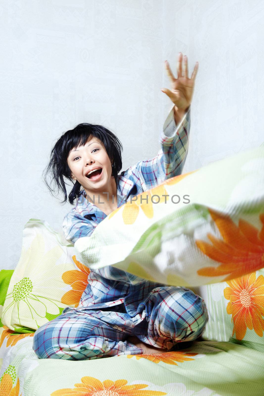 Laughing lady in pajamas playing with pillow