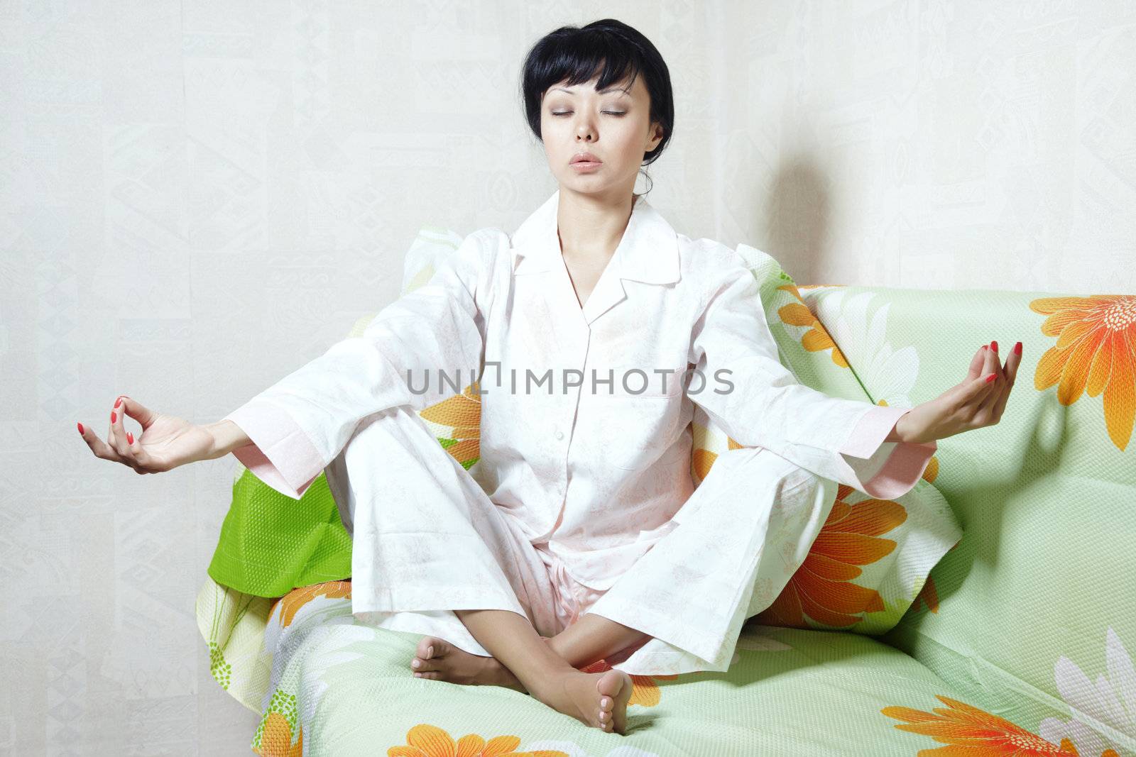 Lady sitting on the bed and doing yoga meditation