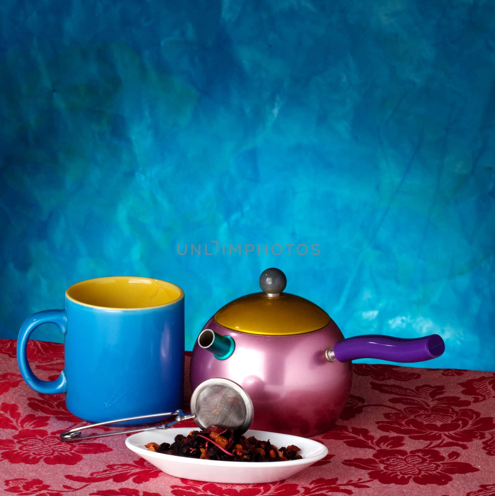 Teapot, cup and herbs on blue background