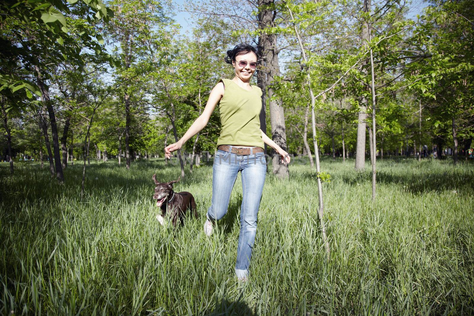 Smiling happy lady runs with her dog in outdoors park