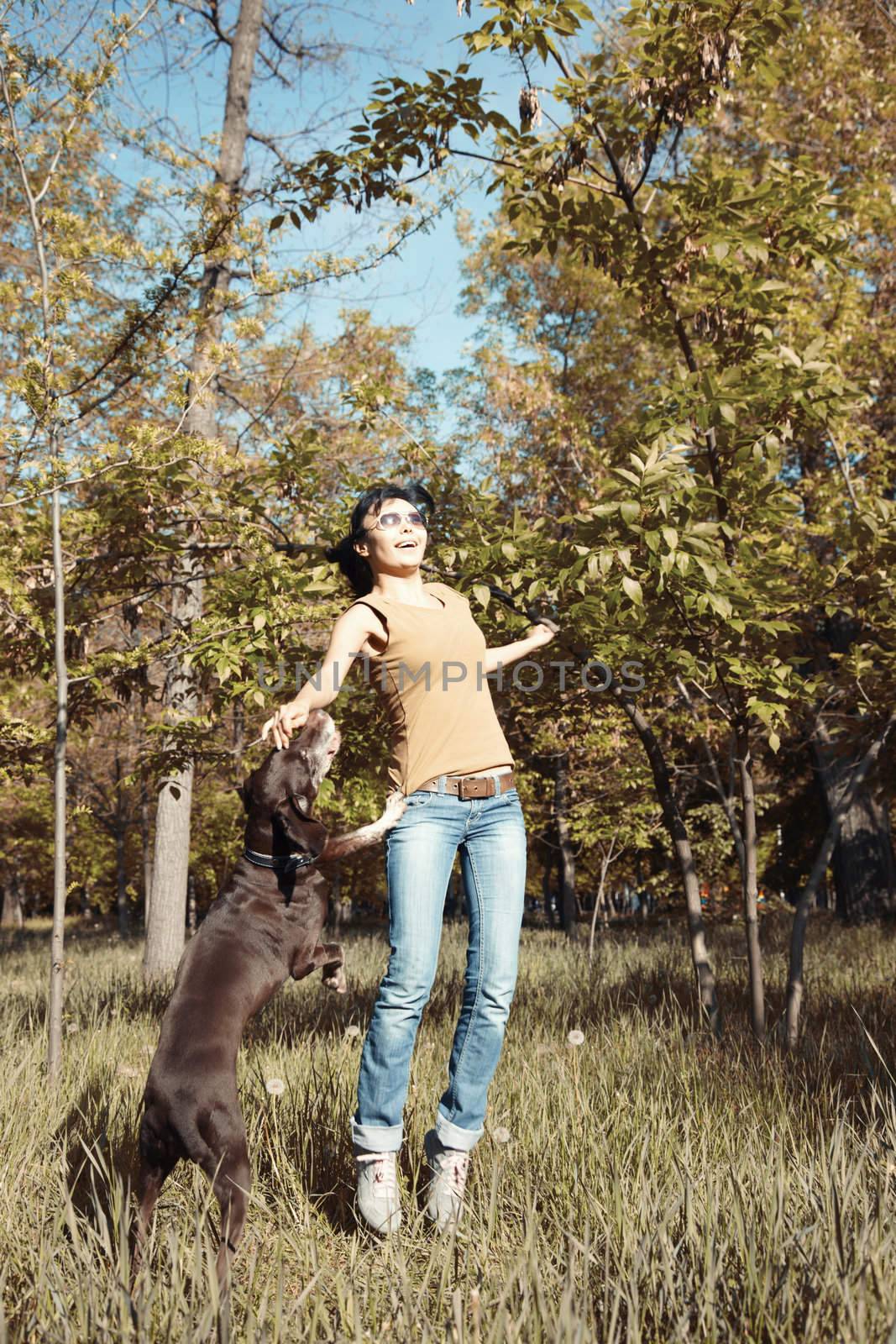 Happy woman playing with dog outdoors