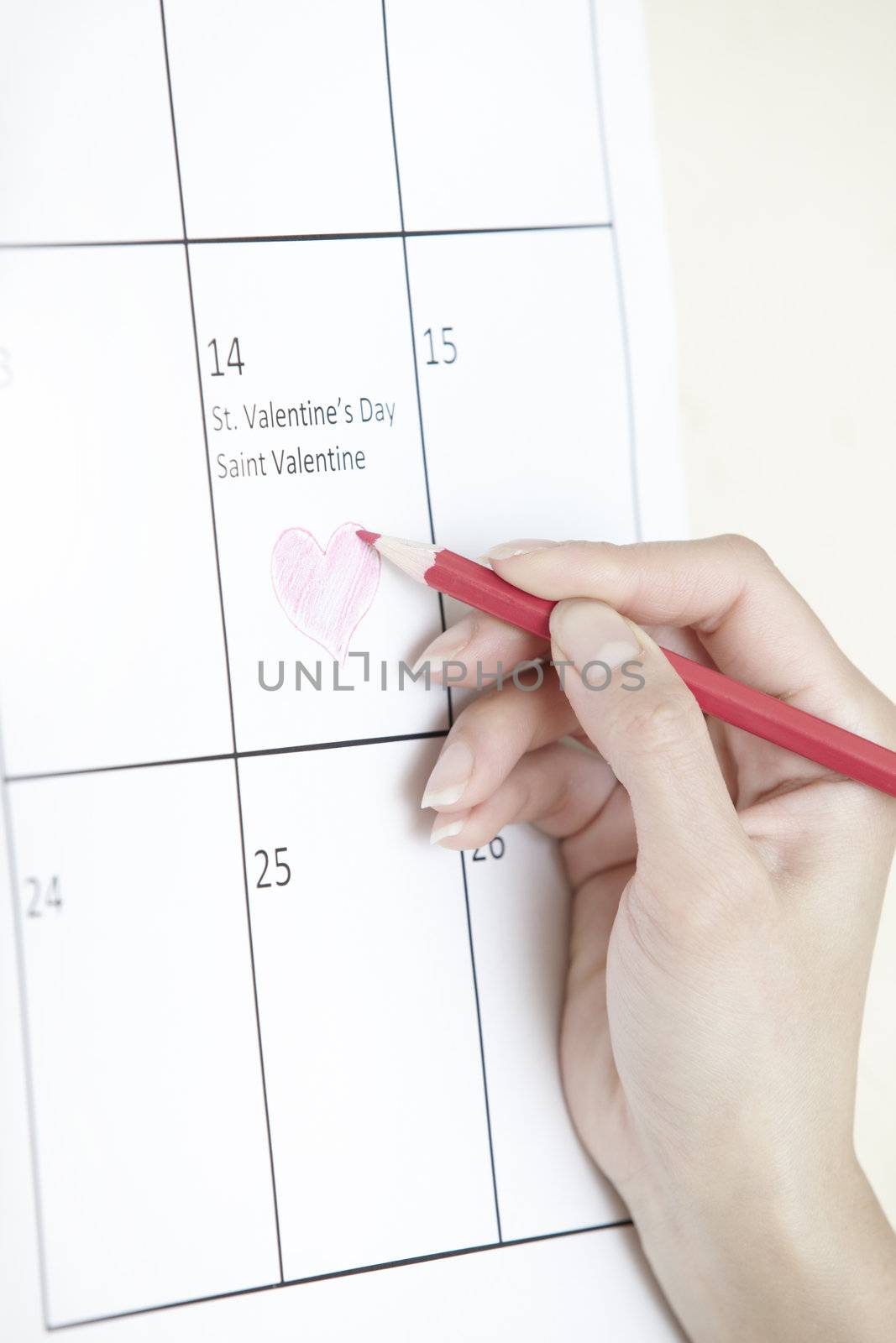 Woman hand drawing heart shape on a calendar
