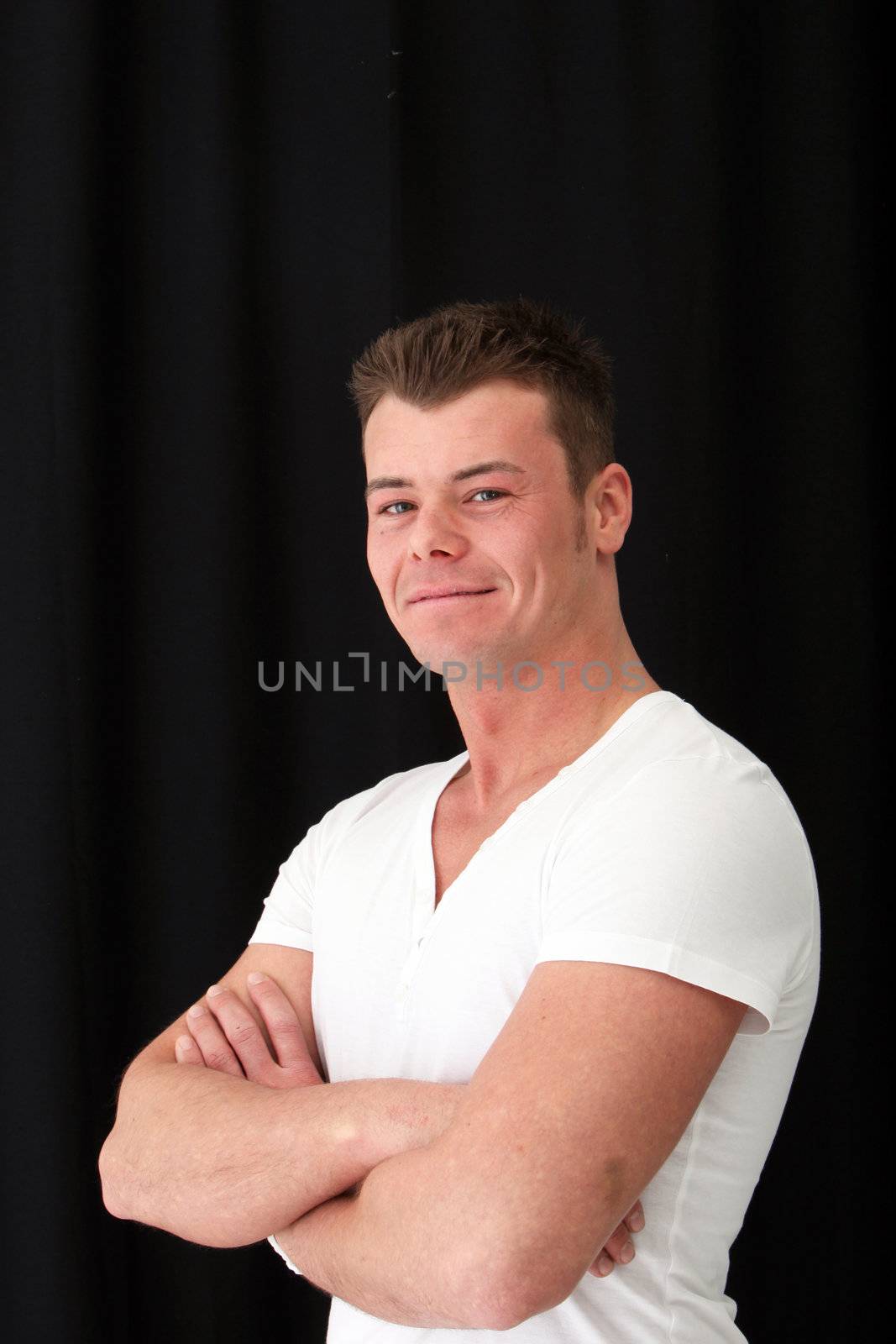 Handsome man posing with arm crossed over the black background