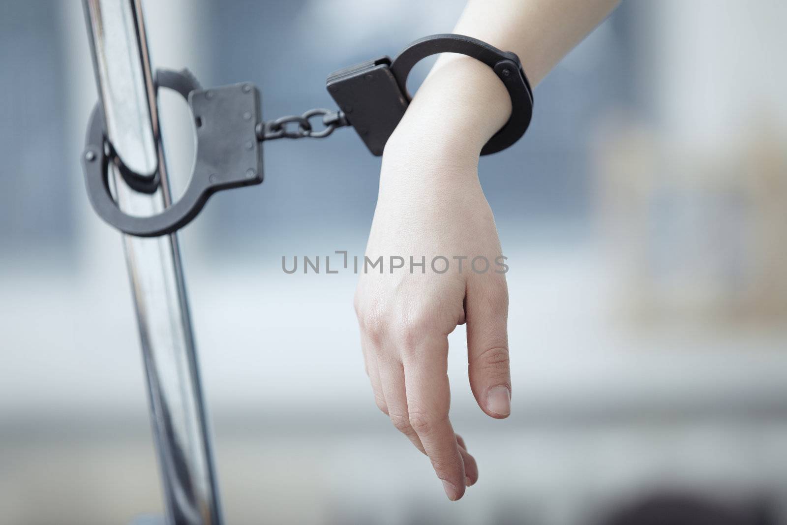 Human hand bounded to the metal pole by handcuffs