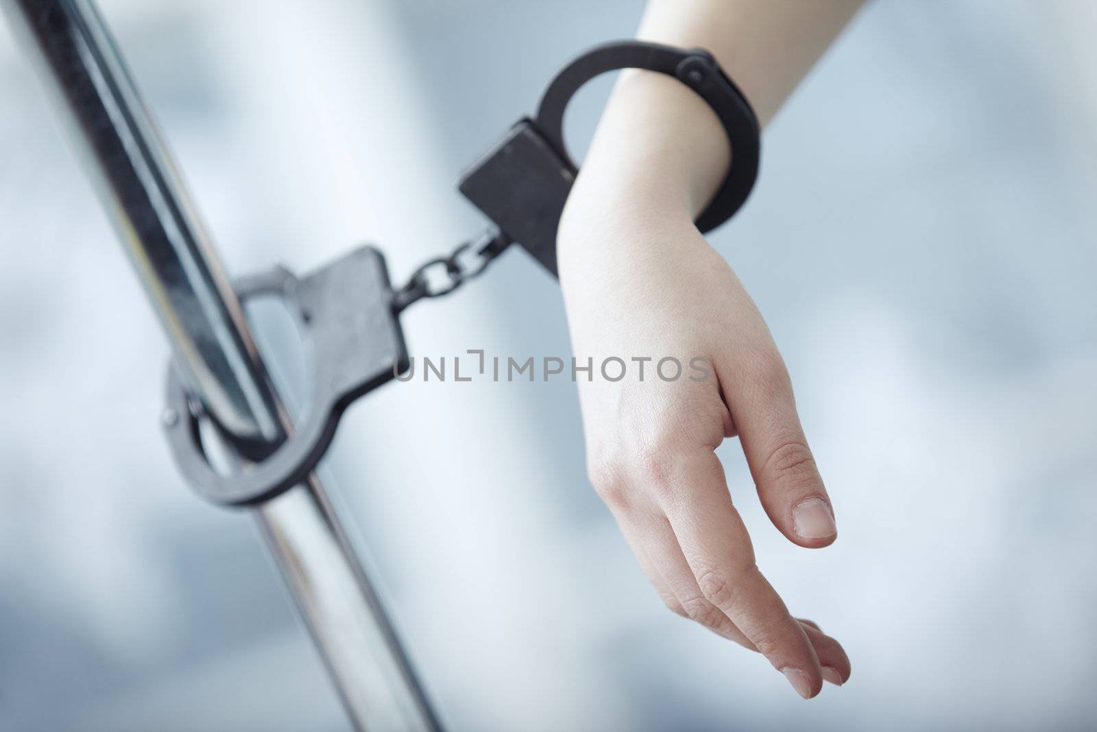 Human hand bounded to the metal pole by handcuffs