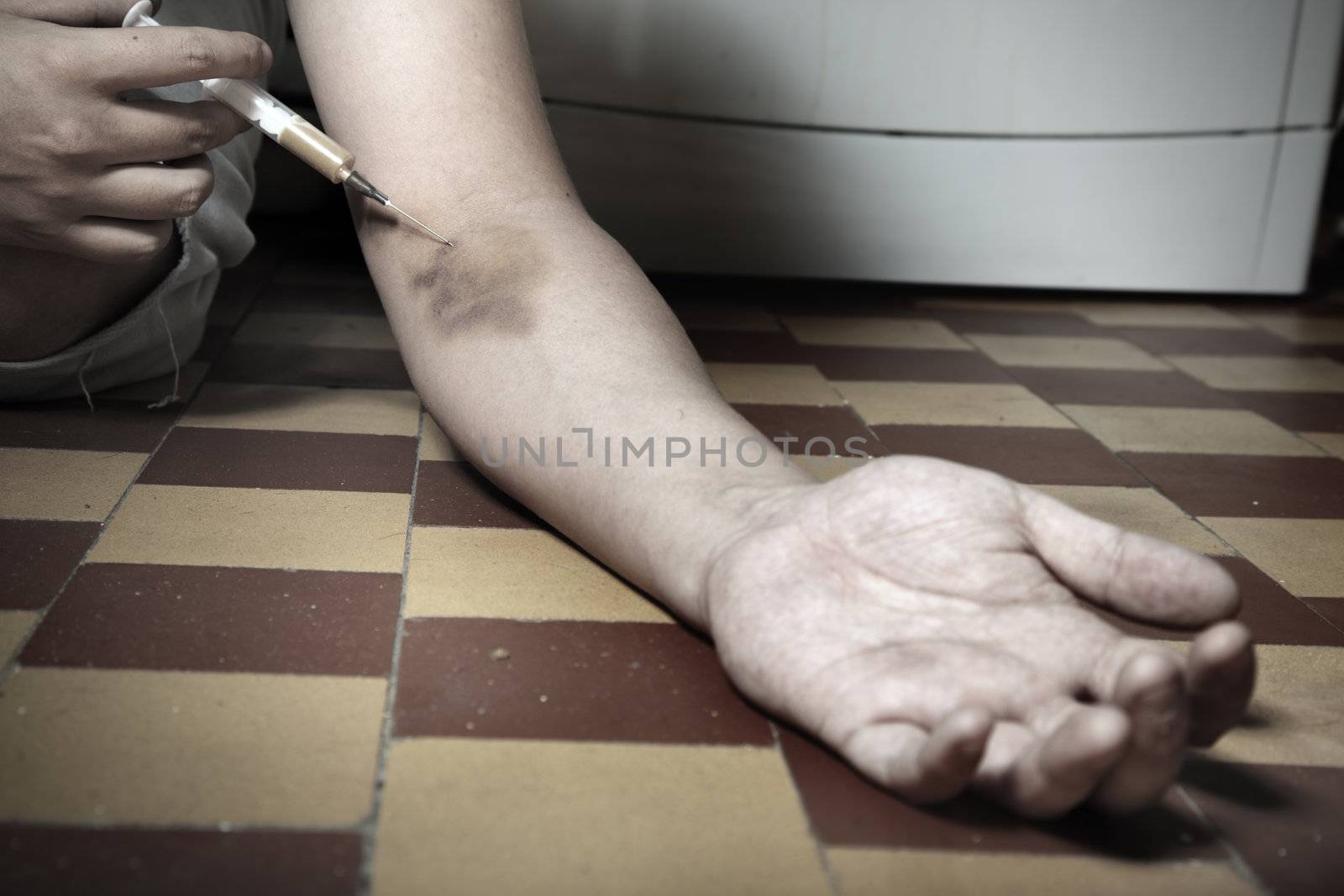 Hand of the narcotist with syringe on the floor. Artistic colors added