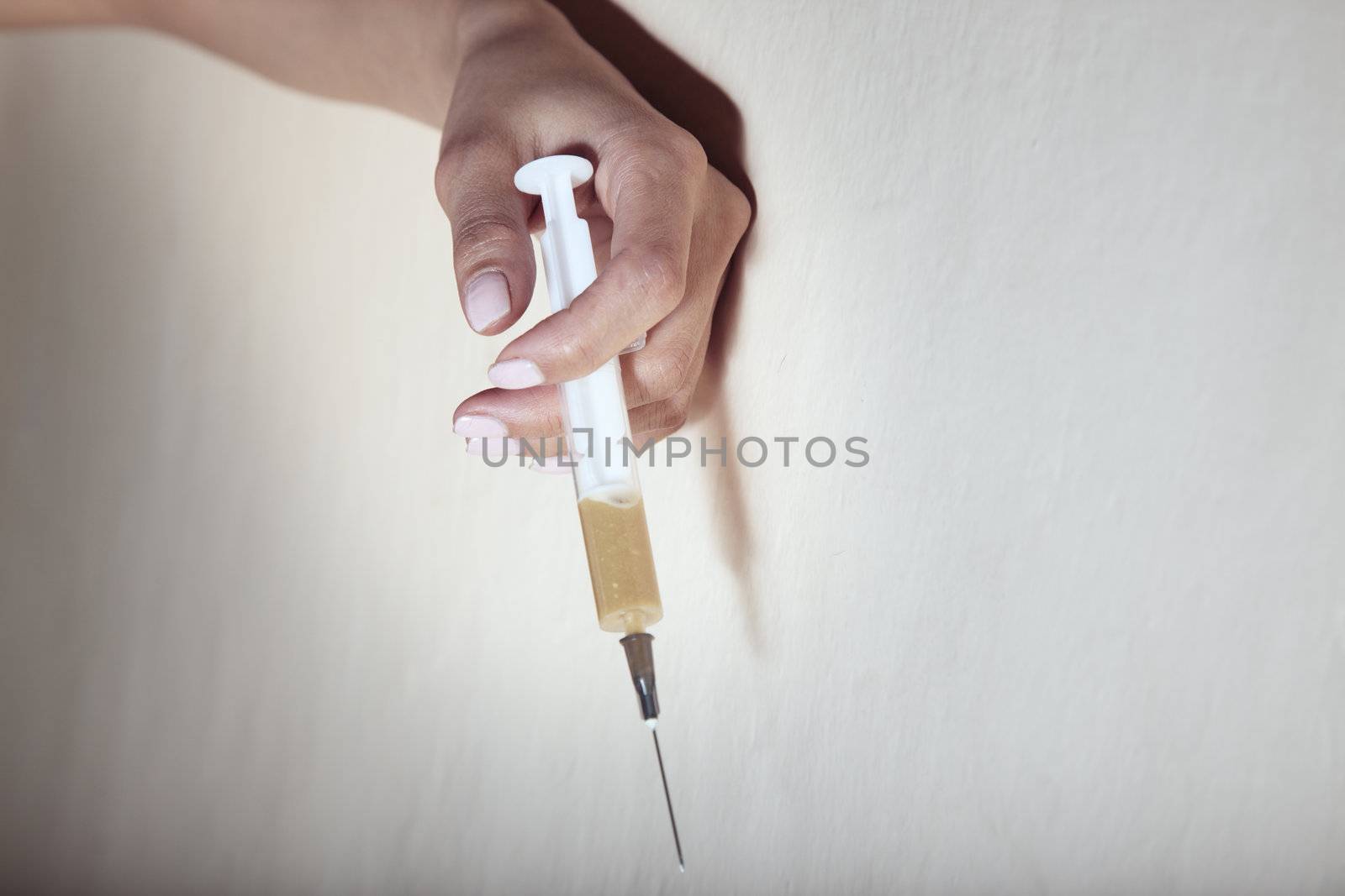 Hand of the narcotist indoors holding syringe with heroin