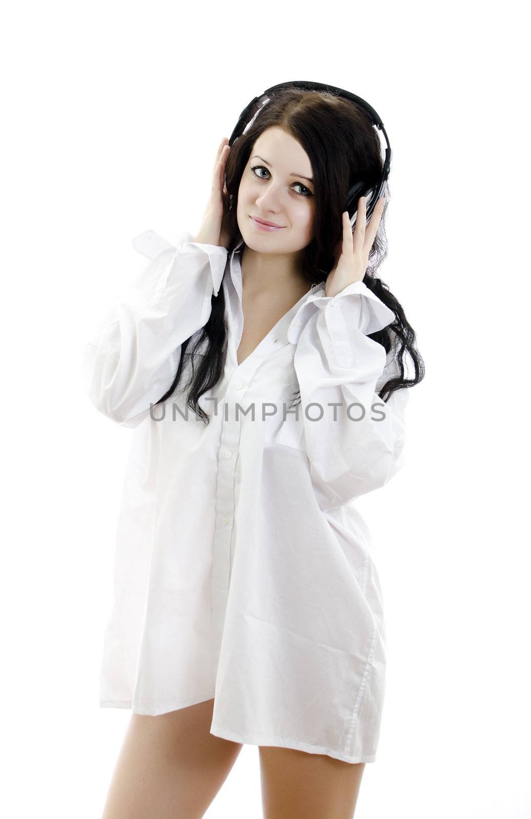 Sensual brunette girl in man's shirt with headphones. Isolated on white.