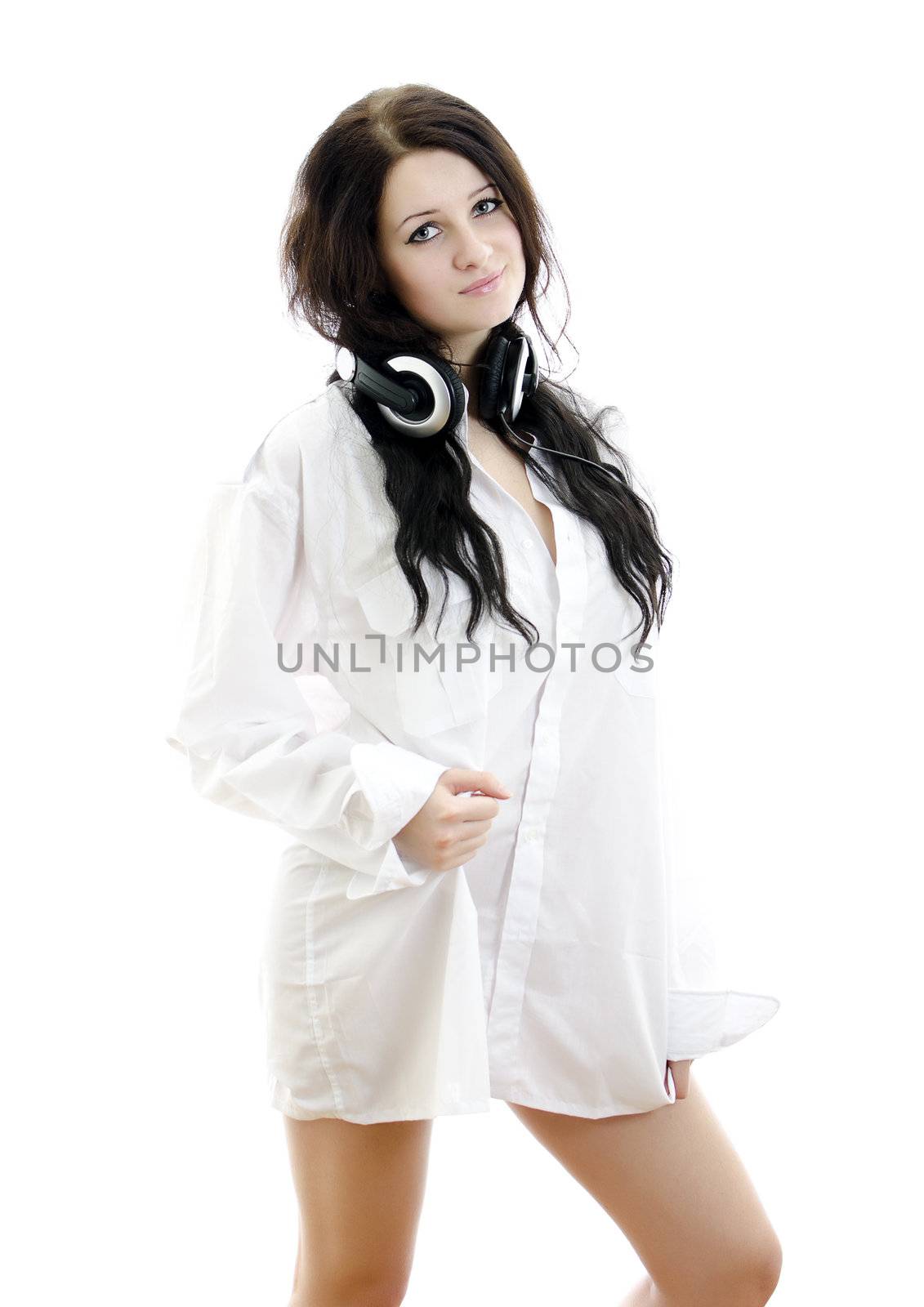 Sensual brunette girl in man's shirt with headphones. Isolated on white.