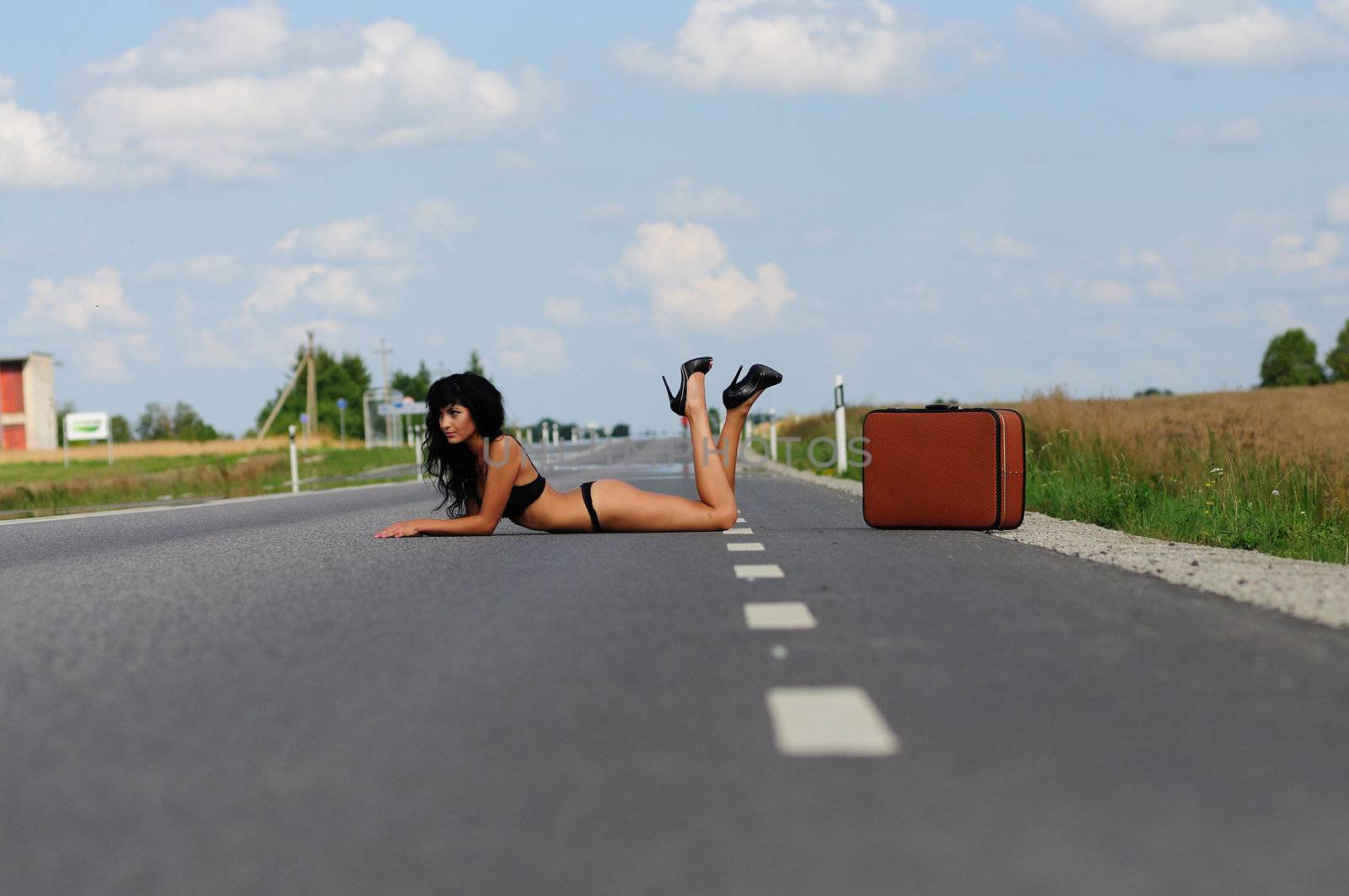 Sexy Traffic Stopper. Gorgeous sexy lady in bikini and stiletto shoes lying across the empty road attempting to block traffic.