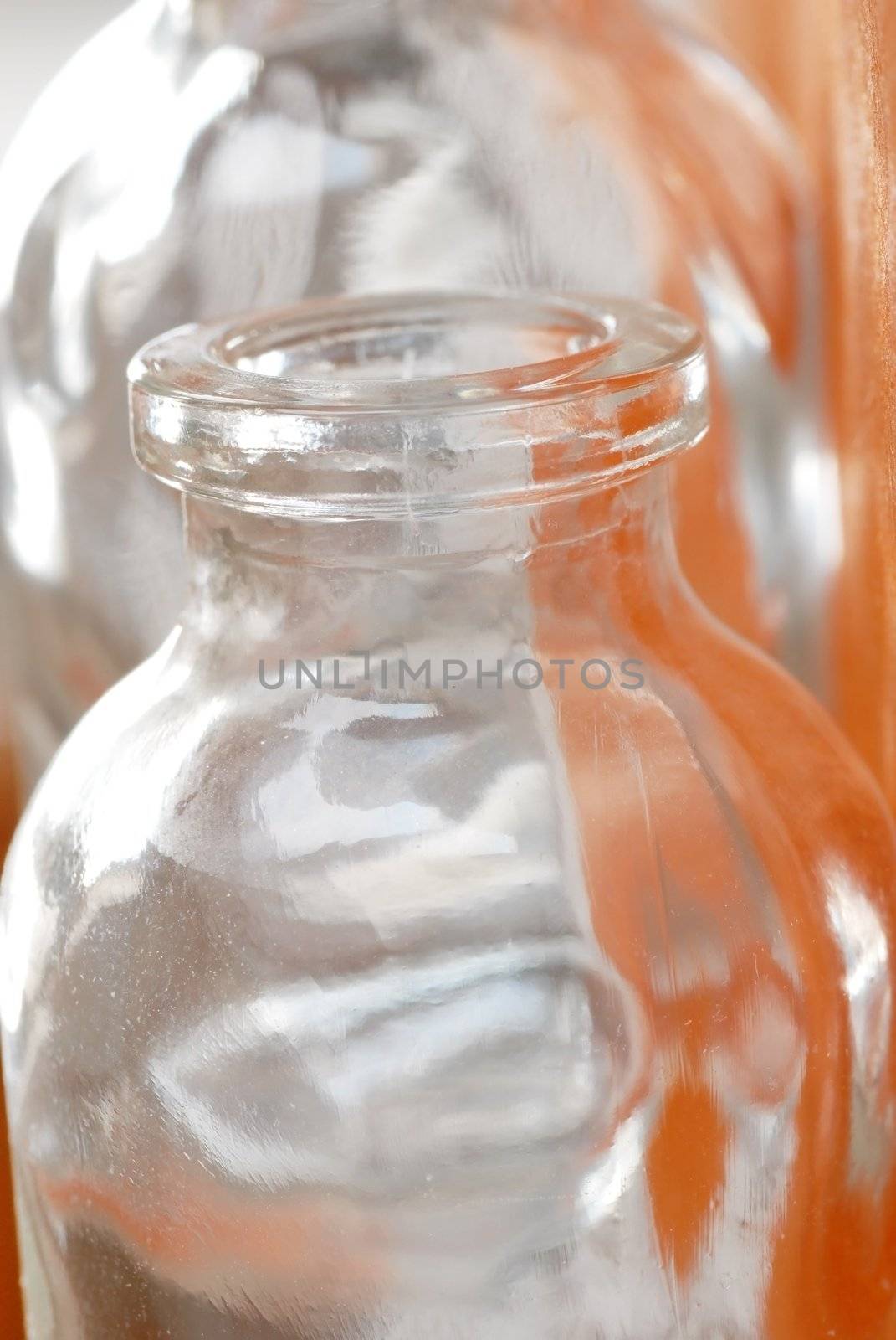 two small empty opened lass bottles  over orange background