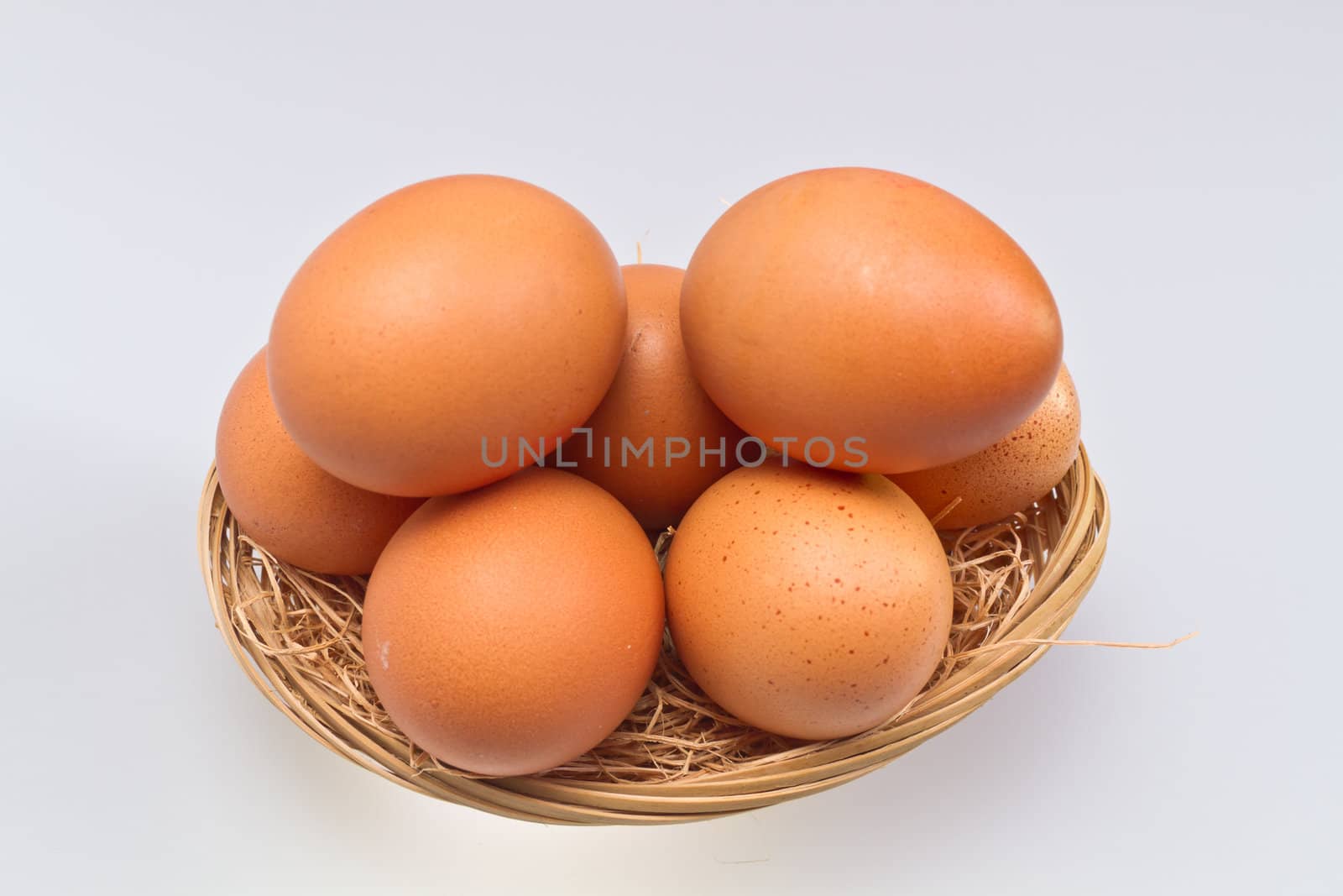brown eggs in rattan basket isolated on whte surface